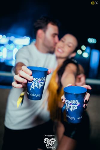 Duas pessoas mostrando copos Ensaios da Anitta